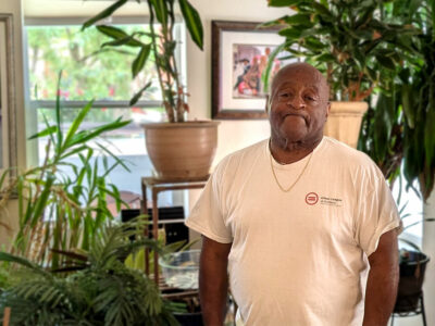 Homeowner stands in front of houseplants and paitnings