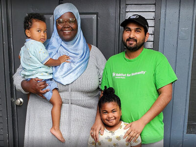 Mohammad and Fatuma stand in front of their home with their small children.