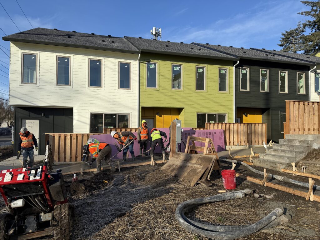 Habitat's King City Commons community during final stages of construction. Crew members are smoothing concrete during sidewalk installation.