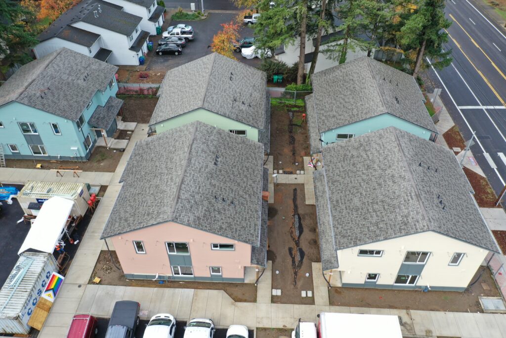 Five complete buildings at Habitat's Myrtlewood Way community in Gresham are visible from an aerial view. They sport bright coats of paint in pinks, greens, and blues.
