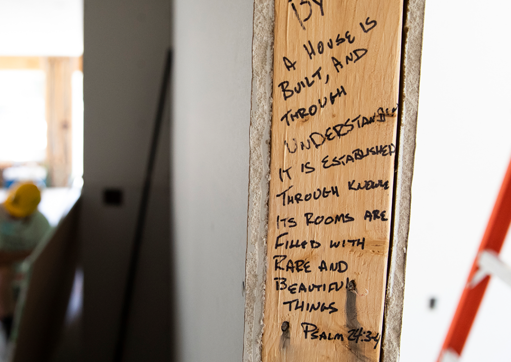 A bible verse written on an unfinished door frame reads: "A house is built, and through understanding it is established. Through knowledge, its rooms are filled with rare and beautiful things."  Proverbs 24: 3-4. 