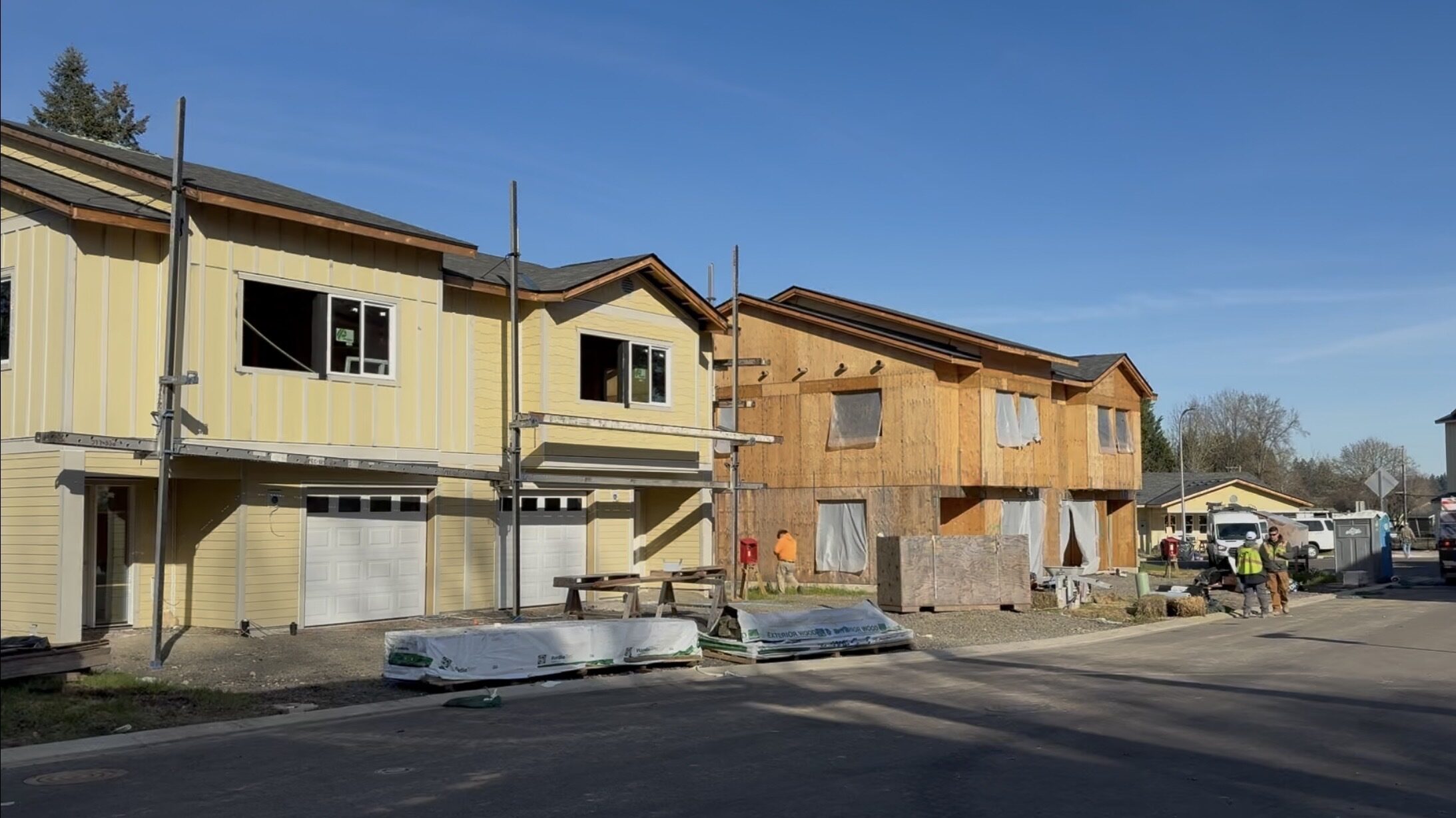 Habitat's Century Commons in January 2025. Two framed homes are visible, one still exposed wood and another covered in yellow siding.