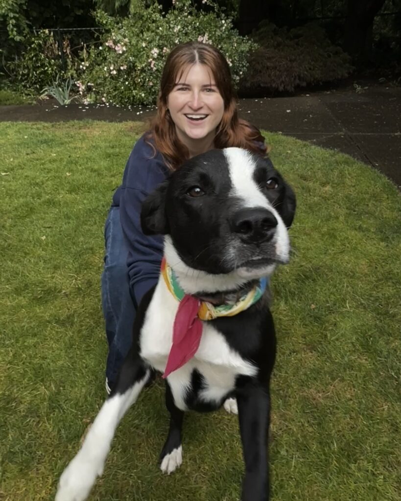 Sophia Dehen beams, holding a black and white dog in her arms for a photo.