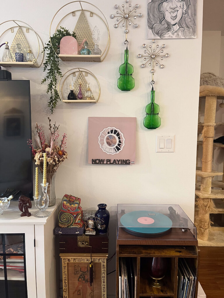 Habitat homeowner Renatta's record player sits beneath her music-themed wall adorned with cello-shaped-vases and record sleeves.