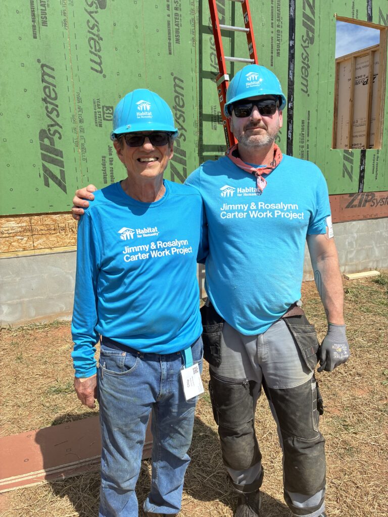 Chip Carter, left, and Jesse Withers, right, stand proudly in front of a Habitat home in progress at the 40th annual Carter Work Project.