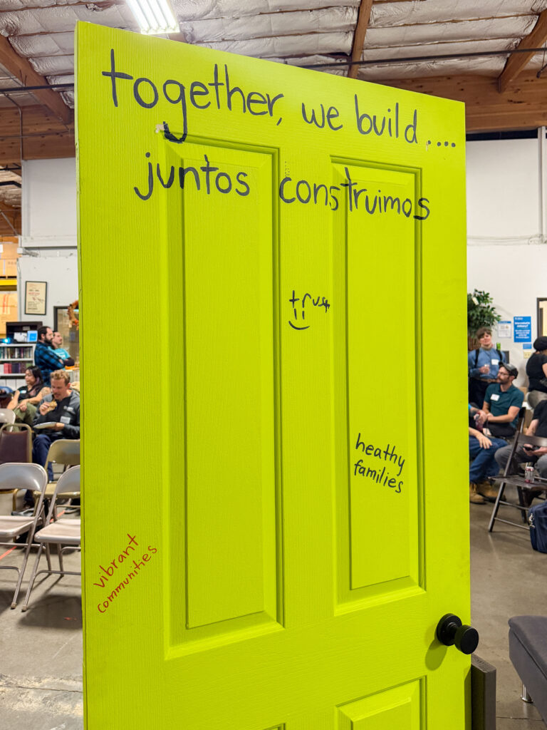 A bright green door reads, "together we build...juntos construimos."